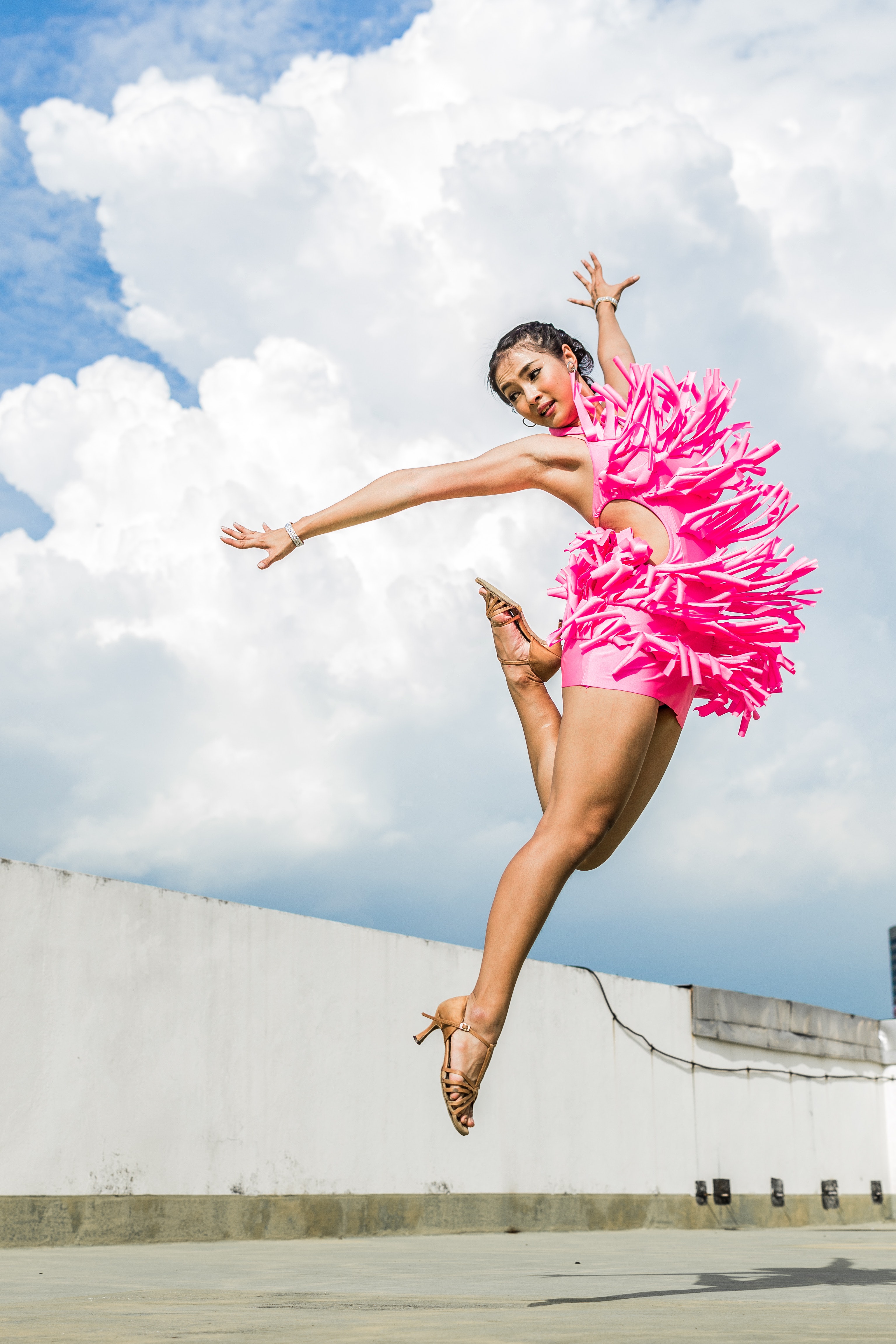 Woman in pink dress doing jump shot while extending arms 690596